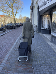 903595 Afbeelding van een vrouw met een boodschappentas op wieltjes op de Oudegracht te Utrecht.